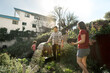 © Cavan Images - Man watering plants while working with friends in community garden