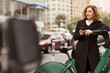 © Cavan Images - Woman using mobile phone while standing by bicycle rack in city