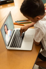 Poster - Male student having a video call with female teacher on laptop at school