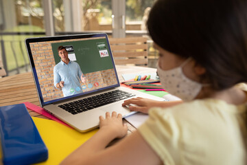 Poster - Female student wearing face mask having a video call with male teacher on laptop at school