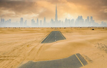 View From Above, Stunning Aerial View Of A Deserted Road Covered By Sand Dunes With The Dubai Skyline In The Background. Dubai, United Arab Emirates.