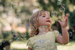 © Cavan Images - Cute baby girl reaching for bubbles flying in air at park