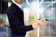 © Cavan Images - Midsection of businessman writing on glass wall while working in office