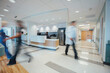 © Cavan Images - Doctor sitting at reception while hospital staff working