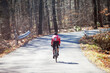 © Cavan Images - Rear view of cyclist riding bicycle on road in forest