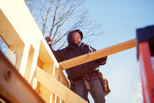 Low Angle View Of Worker Constructing Wooden House Against Blue Sky