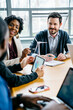 © Cavan Images - Smiling business people at desk during meeting in office