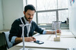 © Cavan Images - Businessman using smart phone while arranging wind turbine models on desk