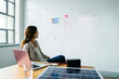 © Cavan Images - Businesswoman looking at diagram on whiteboard while working over solar panel in office