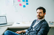 © Cavan Images - Portrait of confident businessman sitting on chair in office