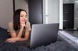 © F8  \ Suport Ukraine - Smiling woman in front of her laptop lying on the bed. Working from home in quarantine lockdown. Social distancing Self Isolation