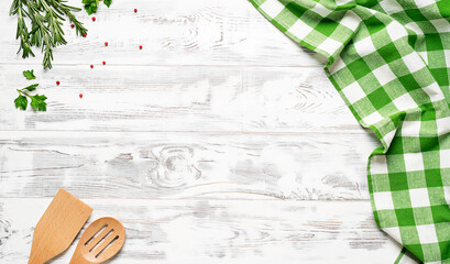 White wooden table covered with green tablecloth and cooking utensils. View from top. Empty tablecloth for product montage. Free space for your text