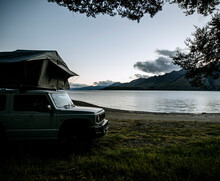 Car With Rooftop Tent At The Edge Of A Lake In New Zealand At Sunset