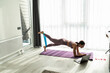 © F8  \ Suport Ukraine - Stay home, stay fit. Happy woman working out with elastic band in front of laptop indoors