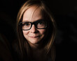 © Cavan Images - Portrait of little girl wearing glasses in low light