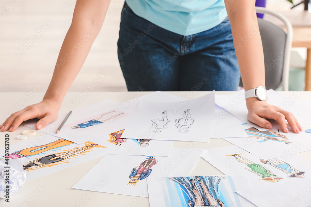 Female fashion designer working with sketches in studio, closeup