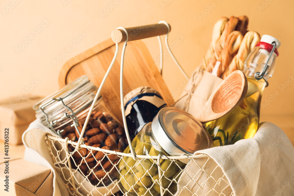 Gift basket with products on color background