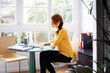 © Cavan Images - Businesswoman sitting on chair while working on laptop in creative office