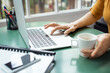 © Cavan Images - Cropped image of businesswoman holding coffee cup while using laptop in office