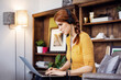 © Cavan Images - Side view of businesswoman wearing headphones while using laptop on chair