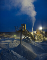 Wall Mural - Details of stone crushing equipment at a mining enterprise in the dark time, long exposure, close-up panorama. Quarry mining machinery.