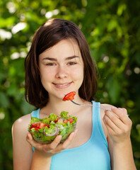 Wall Mural - Girl eating fresh vegetable salad
