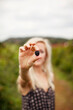 © Cavan Images - Young woman holding fresh blackberry on field against sky