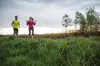 © Cavan Images - Happy friends talking while jogging on grassy field