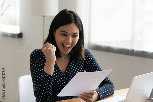 Amazed young mixed race female student hold official written letter with good test exam results. Happy asian woman look at paper document celebrate admission to university receive grant scholarship