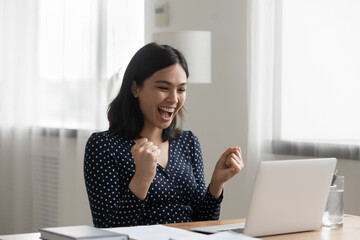 Excited young vietnamese woman look at laptop pc screen in delight receiving good news being accepted admitted to college university. Overjoyed asian lady office worker get reward promotion by email