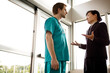 © Cavan Images - Low angle view of doctor talking with businesswoman while standing in hospital