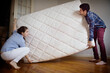 © Cavan Images - Couple carrying mattress in room