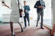 © Cavan Images - Front view of business people walking on corridor in office