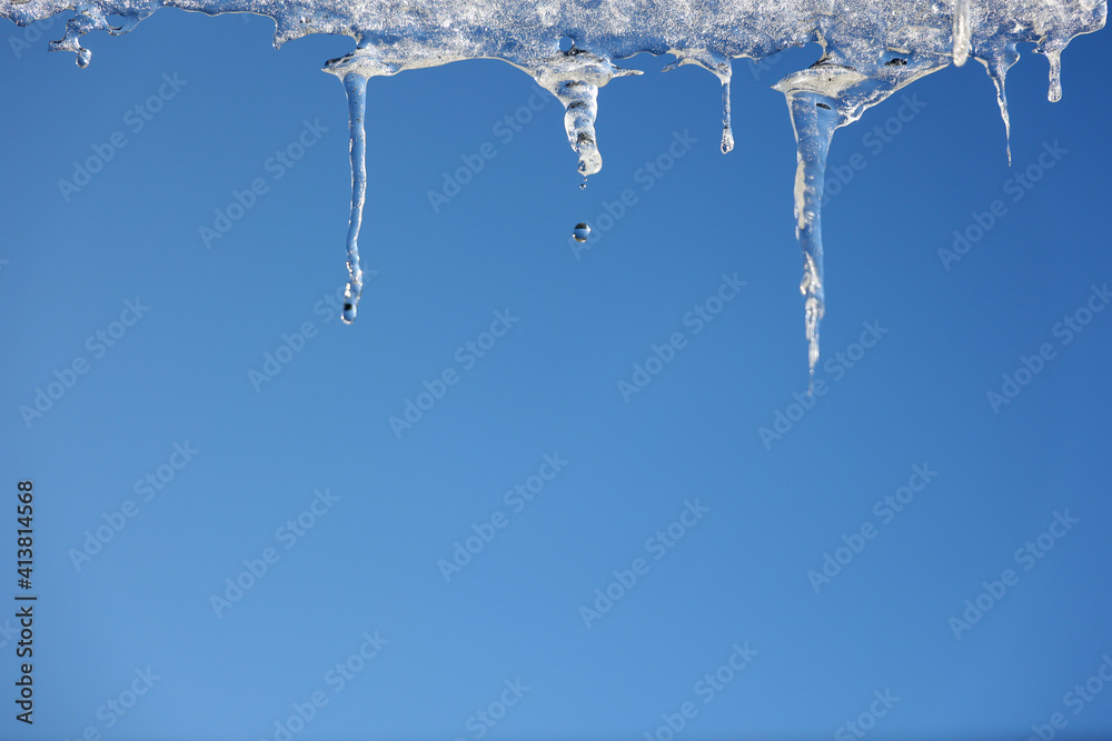 Topniejące sople lodowe na zadaszeniu budynku zimą.  - obrazy, fototapety, plakaty 