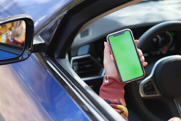 Wall Mural - hand showing green screen smart phone in the car