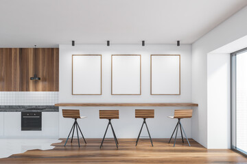 Modern kitchen interior with three white posters on white wall, wooden countertops with a built in cooker. mock up copy space.