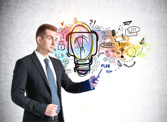 Poster - businessman with phone standing over colourful light bulb on a concrete wall