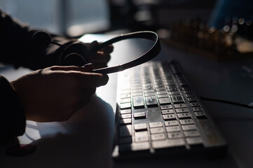 Wall Mural - A woman is holding a headset with a microphone over a computer keyboard. Call center operator's workplace