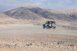 © Cavan Images - White jeep 4x4 driving empty dirty road in desert volcanic landscape
