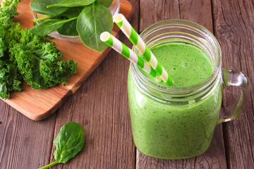 Wall Mural - Green smoothie with kale and spinach in a mason jar glass. Close up scene on a rustic wood background.