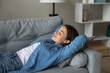 © fizkes - Serene female teenager lying on soft cozy sofa with closed eyes napping having pleasure enjoying comfort peace quiet. Tranquil millennial woman relax on couch at living room sleep in day time dreaming