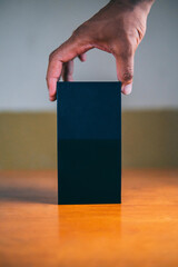 Arima, Trinidad and Tobago - June 6, 2019: A male hand holding a blank black box on top of a table.