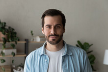 Headshot Portrait Of Handsome Bearded Millennial Man Wearing Casual Clothes. Calm Positive Young Guy Standing Indoors At Home In Office Looking At Camera With Pleasant Confident Smile. Profile Picture