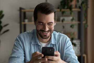 Wall Mural - surfing virtual world. happy smiling bearded millennial male in glasses hold cellphone in hands use 