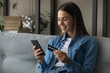 © fizkes - Spending money with pleasure. Happy young female client of reliable bank use card to buy order prepay goods online at web store via special app. Smiling millennial woman engaged in internet shopping