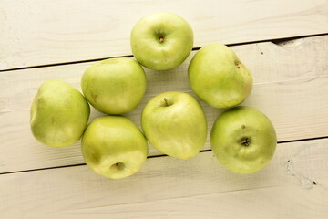 Several ripe green apples on a wooden table, close-up, top view.