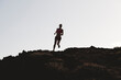 © Cavan Images - Silhouette of a woman running on a rocky trail