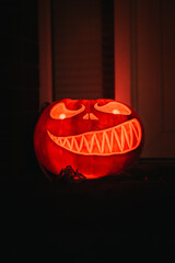 Poster - Closeup view of a carved pumpkin with candles inside of it in the dark room - Halloween concept