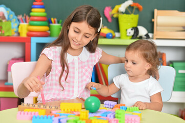 Wall Mural - Two little girls playing with colorful plastic blocks