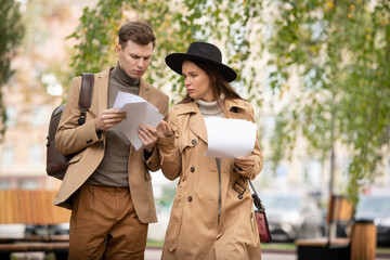 Poster - Two young serious economista in smart casualwear looking through papers